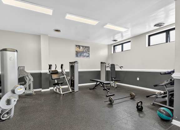 A gym with a variety of equipment including weights and a bench.