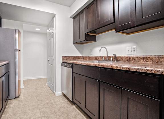 a kitchen with dark cabinets and a sink and a refrigerator