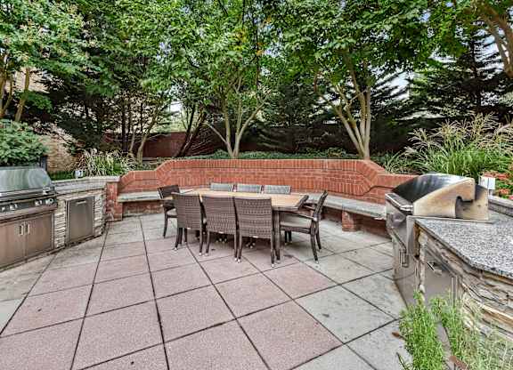 A patio with a table and chairs surrounded by trees.