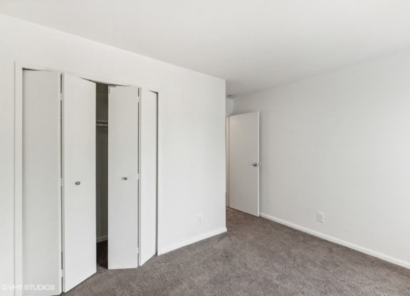 a bedroom with white walls and mirrored closet doors