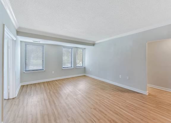 A room with wooden flooring and a window with blinds.