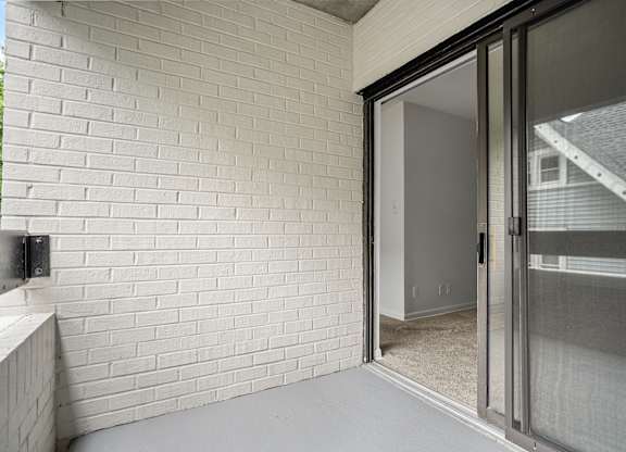 a sliding glass door opens to a patio in a home with a brick wall