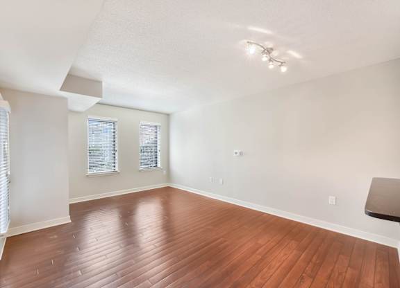 A room with wooden flooring and a window with blinds.