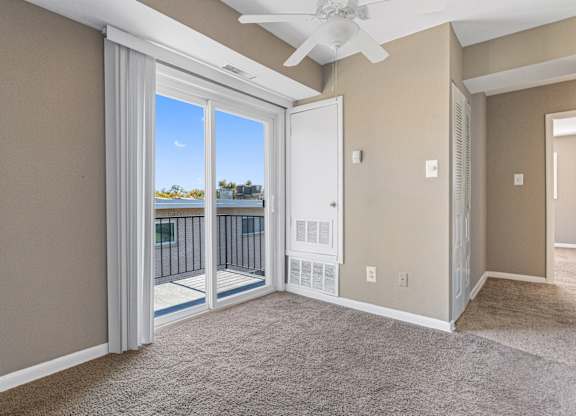 A room with a carpeted floor and a ceiling fan.