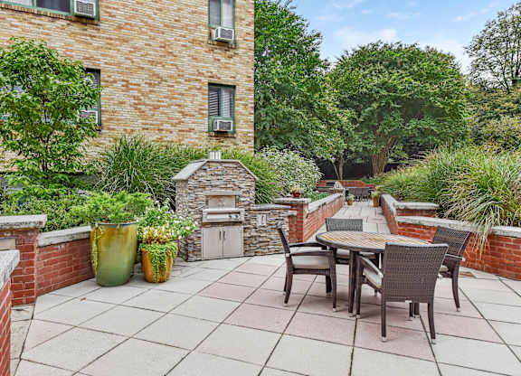A patio with a table and chairs is surrounded by a brick wall and has a fireplace.