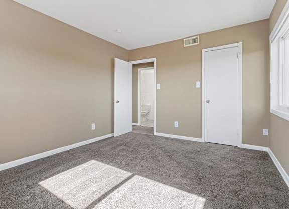 A room with a carpeted floor and two white doors.