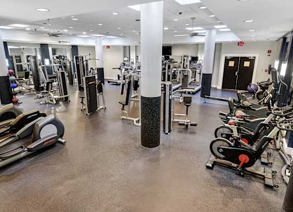 A gym with a variety of equipment including treadmills, weights, and exercise machines.