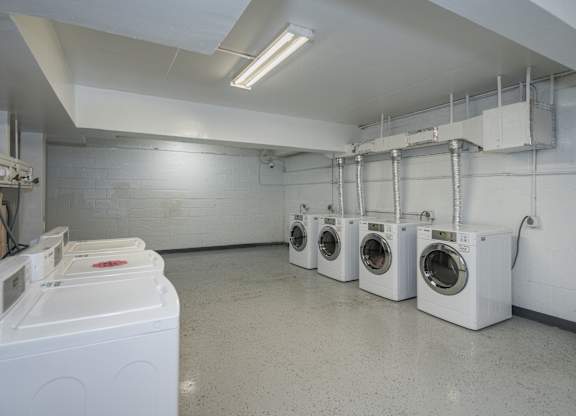 A laundry room with washing machines and a white wall.