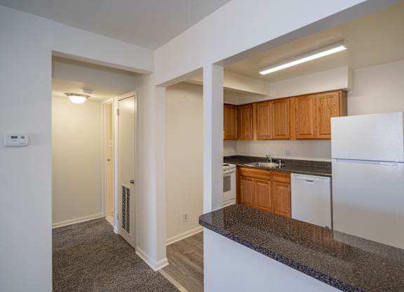 A kitchen with white appliances and wooden cabinets.