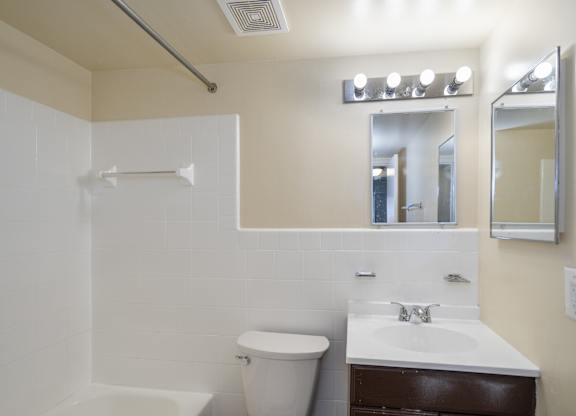 A white bathroom with a toilet, sink, and mirror.