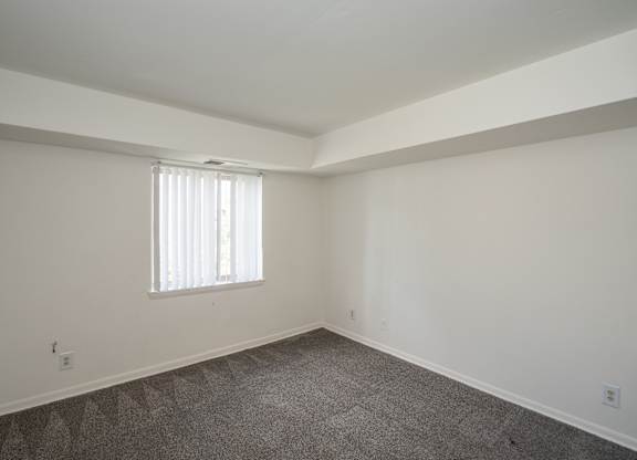 A room with a window and carpeted floor.