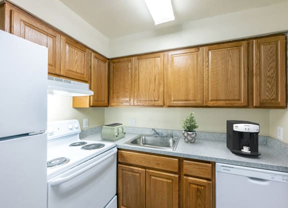 an empty kitchen with white appliances and wooden cabinets
