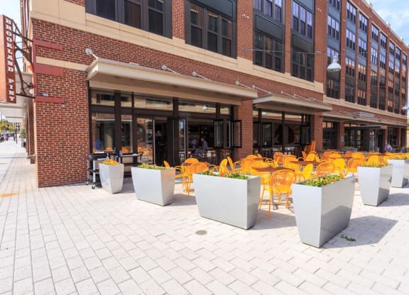 a row of yellow chairs and tables outside of a building