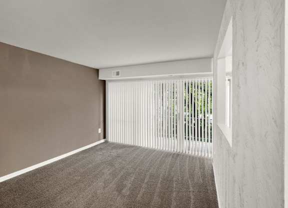 an empty living room with white blinds and a window