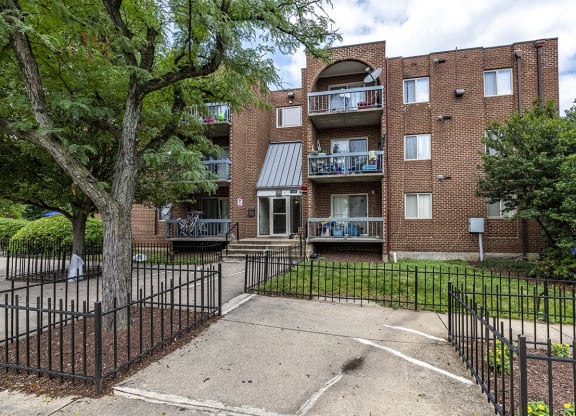 an apartment building with a yard and a wrought iron fence
