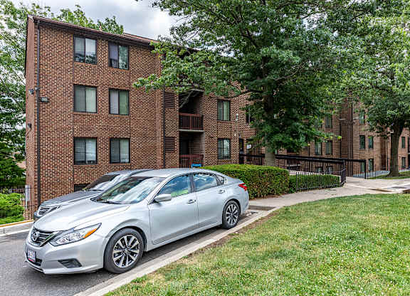 a silver car parked in front of a brick apartment building