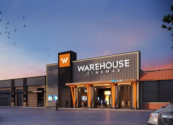 A Warehouse Cinemas building with cars parked in front.