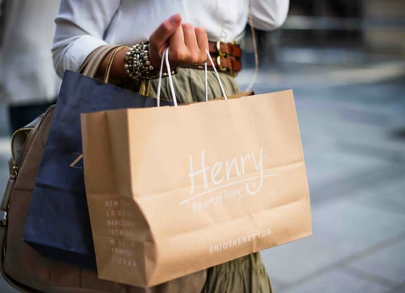 a woman holding a paper bag with her shopping bags