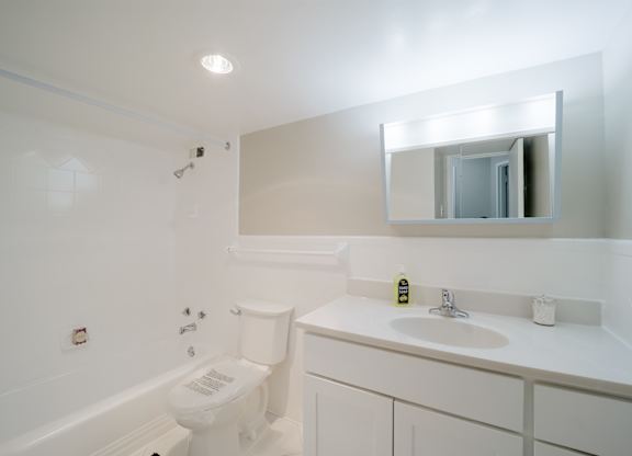 A white bathroom with a toilet, sink, and mirror.