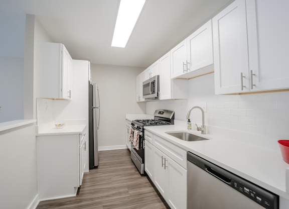 A kitchen with white cabinets and appliances.