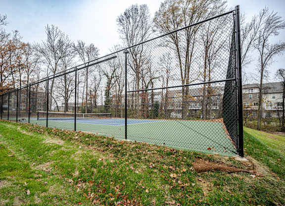 A tennis court is enclosed by a black fence.