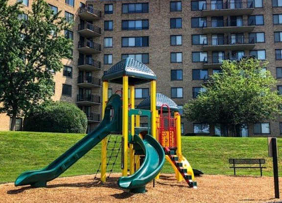 A playground with a green slide and a yellow and red tower.