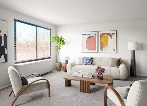 A living room with a white couch, a wooden coffee table, and a large window.