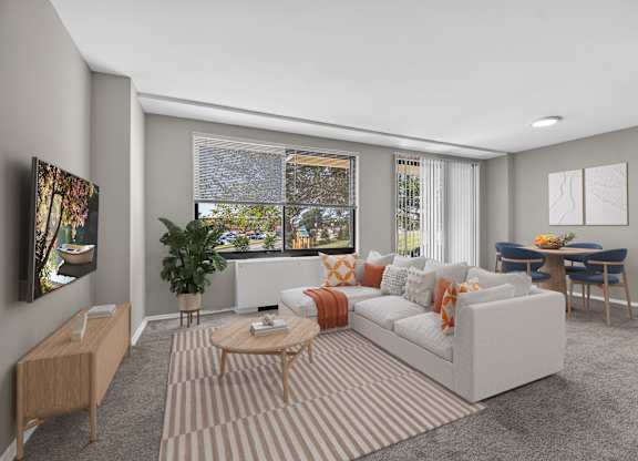 A living room with a white sofa, a wooden coffee table, and a TV on the left side.
