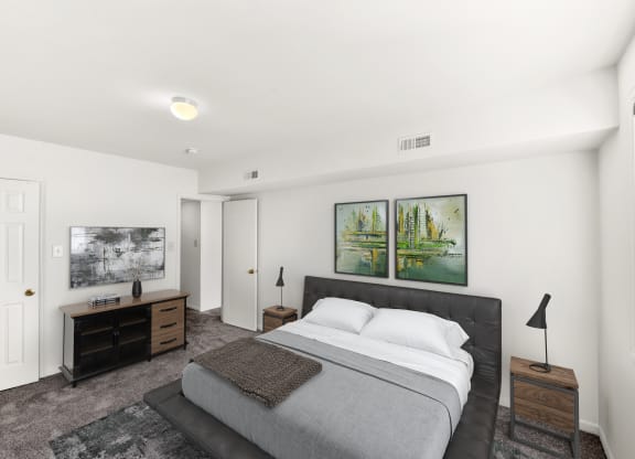 a white bedroom with a bed and two paintings on the wall