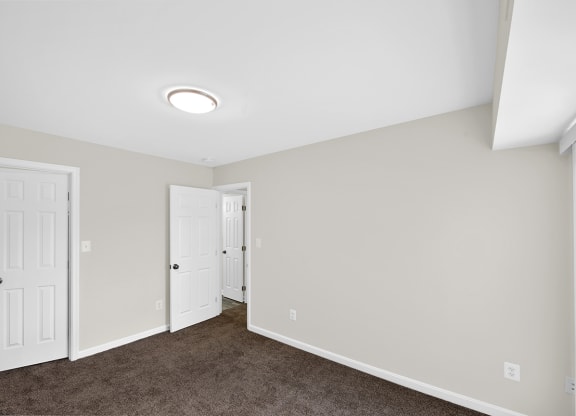 an empty room with a carpeted floor and white doors