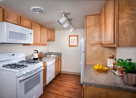 a kitchen with white appliances and wooden cabinets and a counter top
