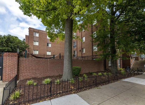 a brick building with a tree in front of a fence