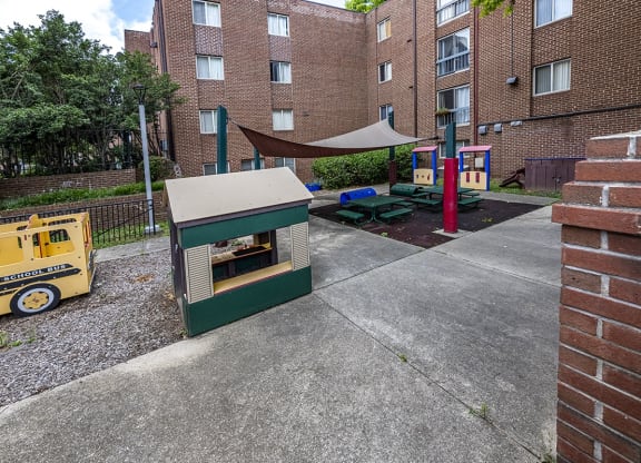 a play area with a hot dog cart in front of a brick building