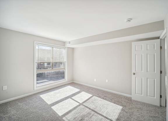 A room with a white door and a window with a view of a street.