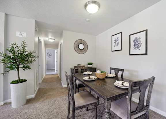 A dining room with a table set for two and a plant in a white pot.