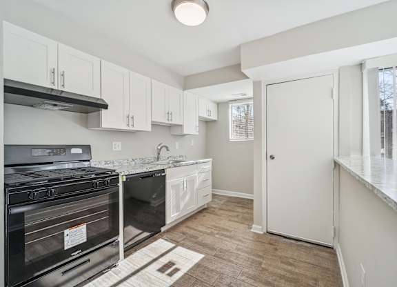 A kitchen with a black stove top oven and white cabinets.