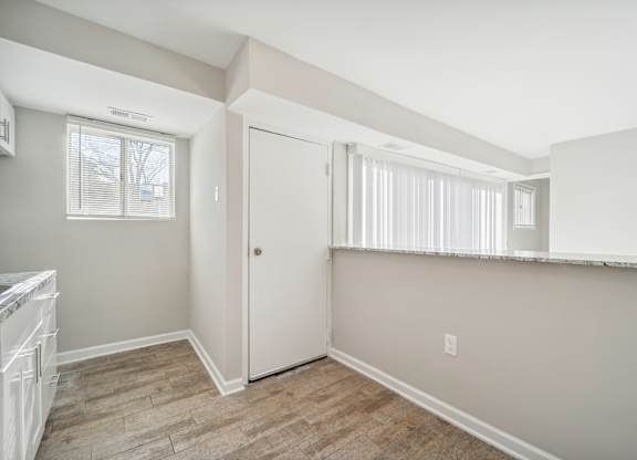 A room with a white door and a window with white blinds.