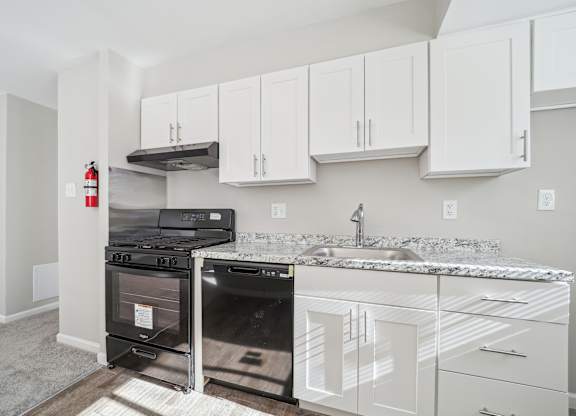A kitchen with white cabinets and a black stove top oven.