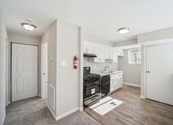 A kitchen with a white door and a red fire extinguisher on the wall.
