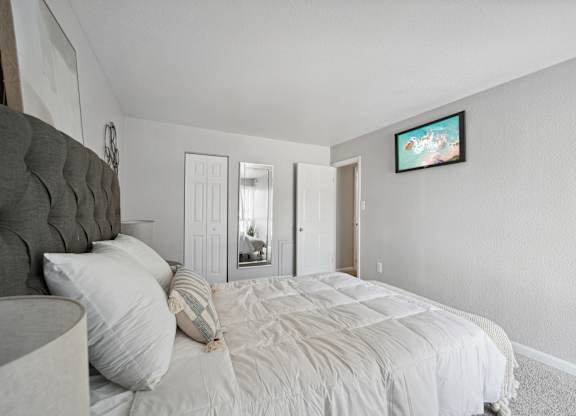 A bedroom with a large bed and a flat screen TV mounted on the wall.