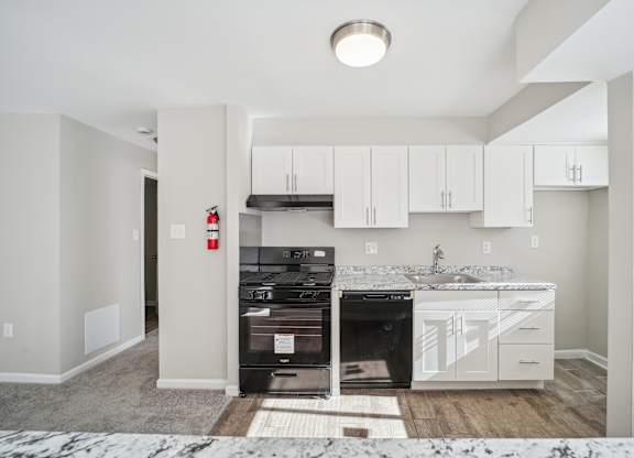A kitchen with a black oven and white cabinets.