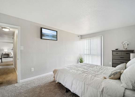 A bedroom with a large bed and a television mounted on the wall.