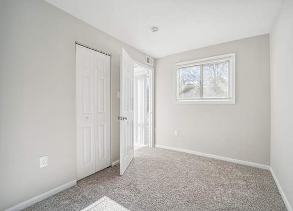 A room with a carpeted floor and a window with blinds.
