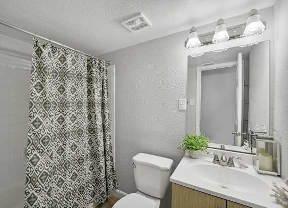 A bathroom with a toilet, sink, and shower curtain.