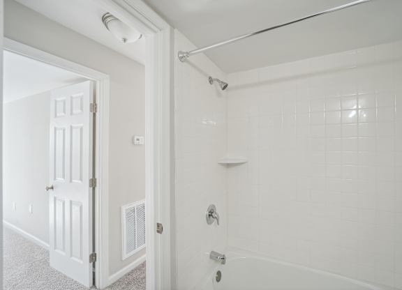 A white bathroom with a white door and a white shower.
