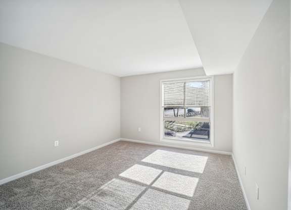 A room with a large window and a carpeted floor.