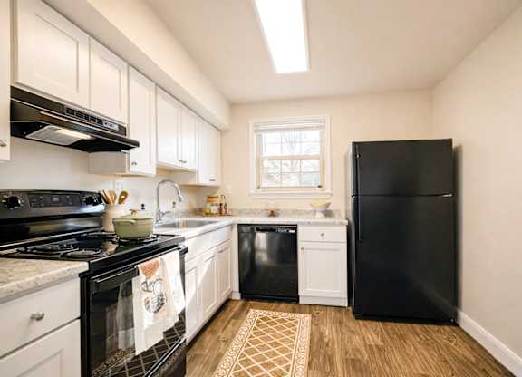 Modern kitchen with white cabinets and black appliances at Highland Ridge Apartments, Capitol Heights, MD