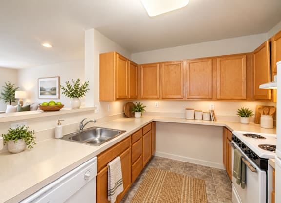 A kitchen with wooden cabinets and a white countertop at River Point Apartments, Maryland