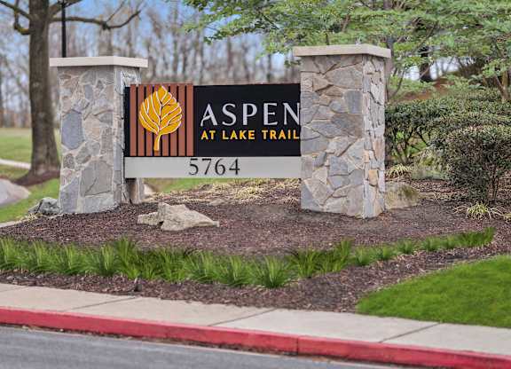 A sign for Aspen at Lake Trail with a phone number on it.
