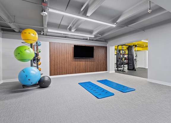A room with a blue mat on the floor and a TV on the wall.
